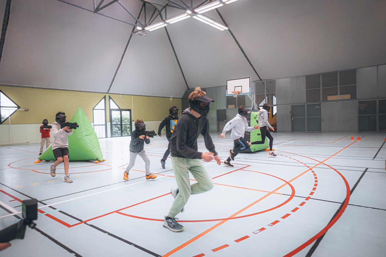 Energetic teenagers in action during an indoor laser tag game in a sports hall.