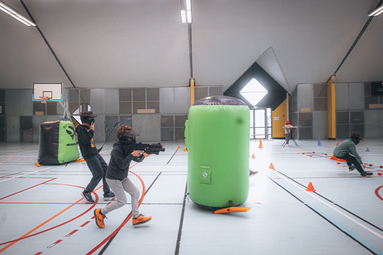 Energetic teenagers playing an indoor laser tag game with vibrant inflatables and obstacles.